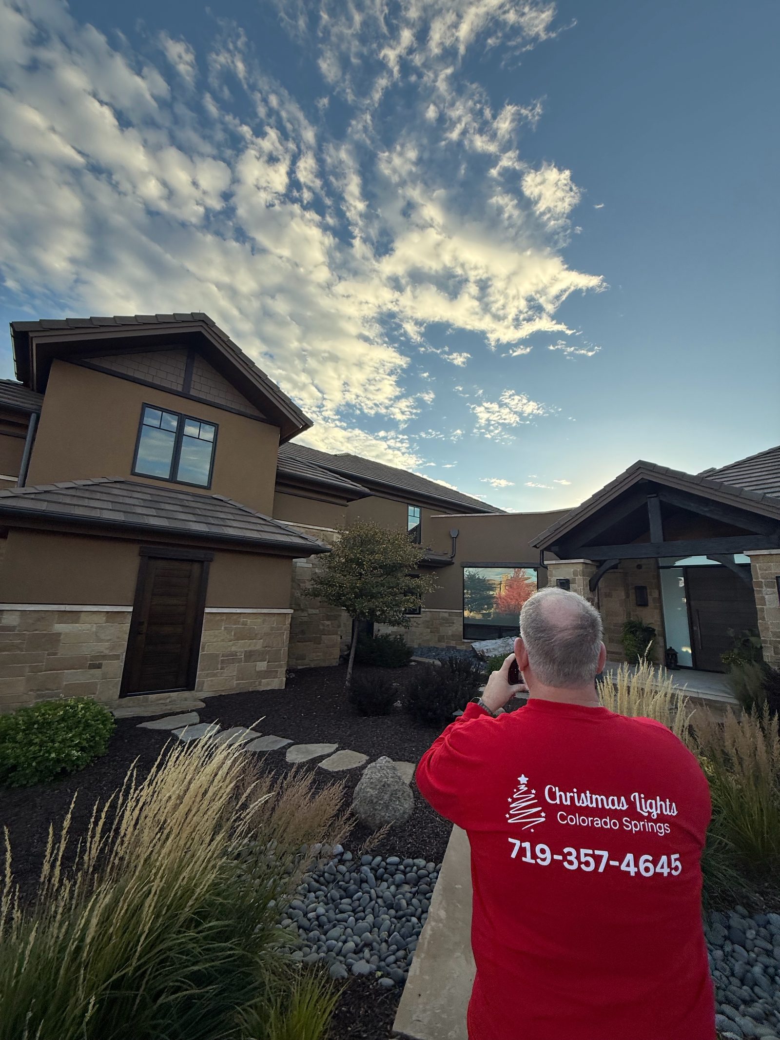 Christmas Lights Colorado Springs technician in branded shirt photographing a finished holiday lighting install Christmas Lights Colorado Springs technician in branded shirt photographing a finished holiday lighting install
