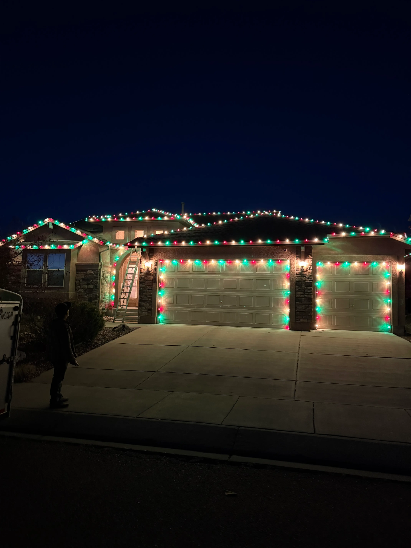 Christmas lights design example - professional holiday lighting on residential home with red and green LED roofline lights, garage door lighting, and complete outdoor display